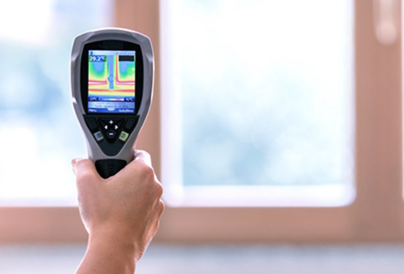 Bild eines Handwerkers, der mit einem speziellen Gerät eine Thermografie durchführt.
